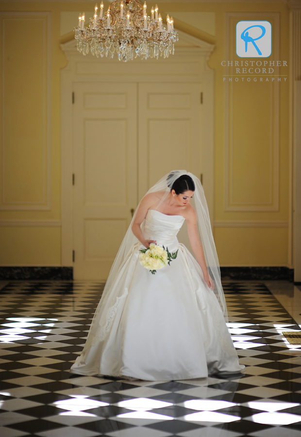 Bride fixes her dress during portrait sessin at Duke Mansion